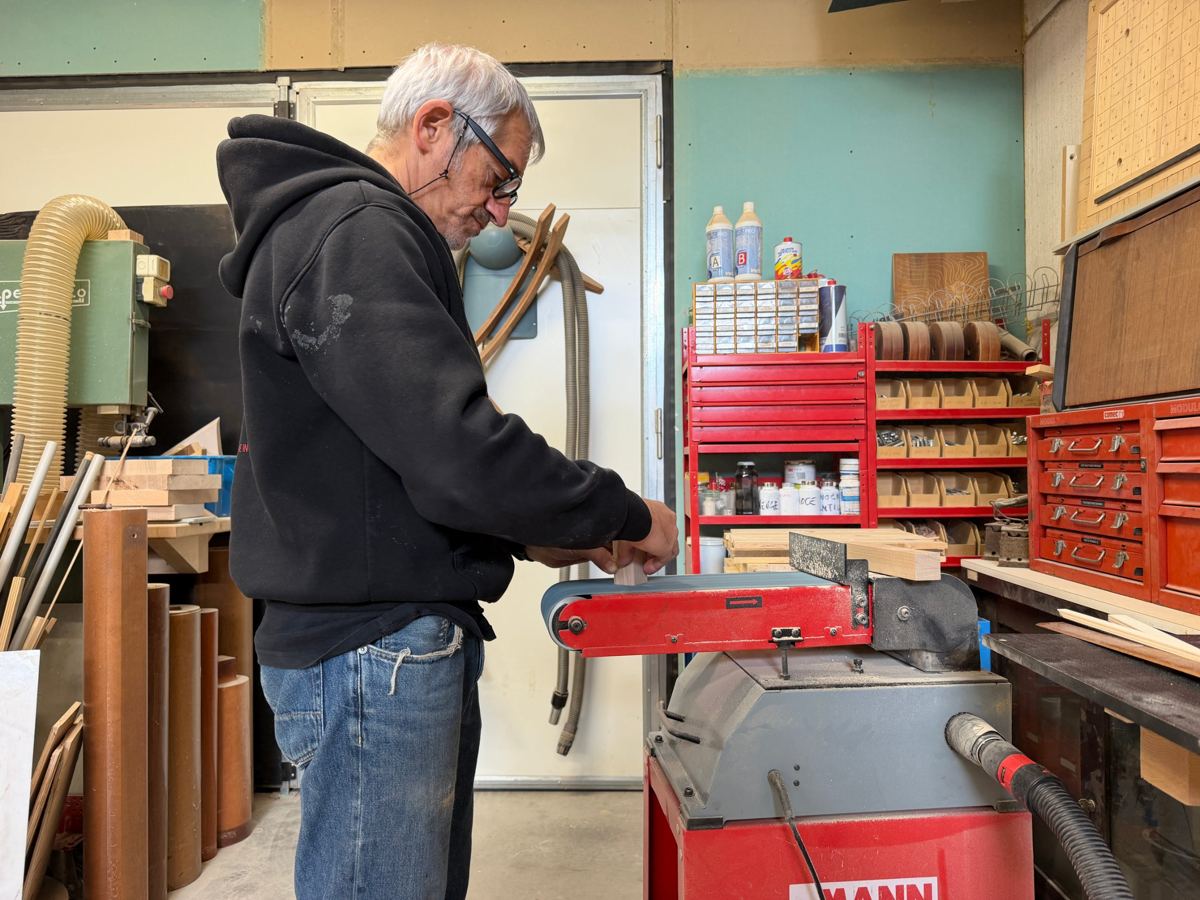 Fabrizio Berlati al lavoro nel suo laboratorio di Cesena mentre leviga un pezzo di legno alla levigatrice a nastro