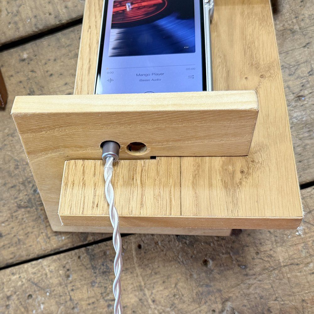 Lettore digitale appoggiato sul supporto in legno, con il cavo delle cuffie
